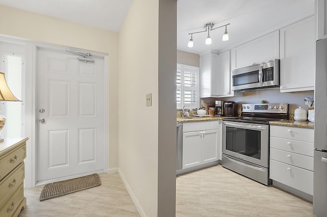 kitchen with dark stone countertops, sink, white cabinets, and appliances with stainless steel finishes