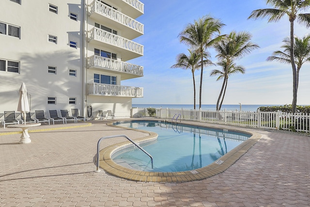 view of swimming pool featuring a patio and a water view