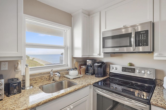 kitchen with stainless steel appliances, sink, white cabinets, and light stone counters