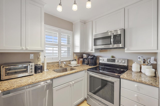 kitchen featuring sink, light stone counters, decorative light fixtures, stainless steel appliances, and white cabinets