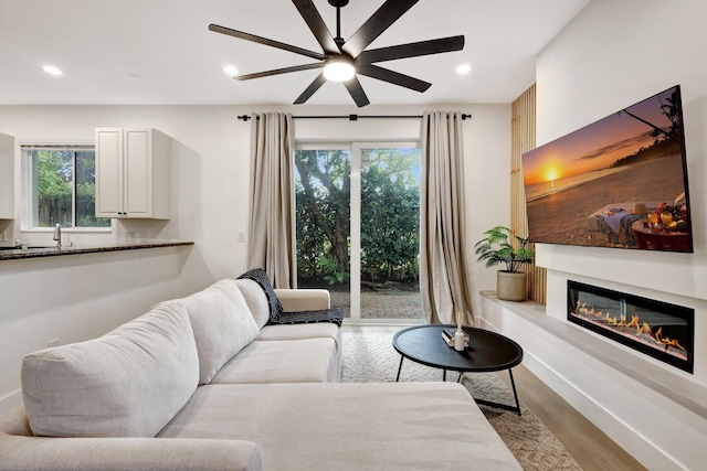 living room featuring ceiling fan, a wealth of natural light, and light wood-type flooring