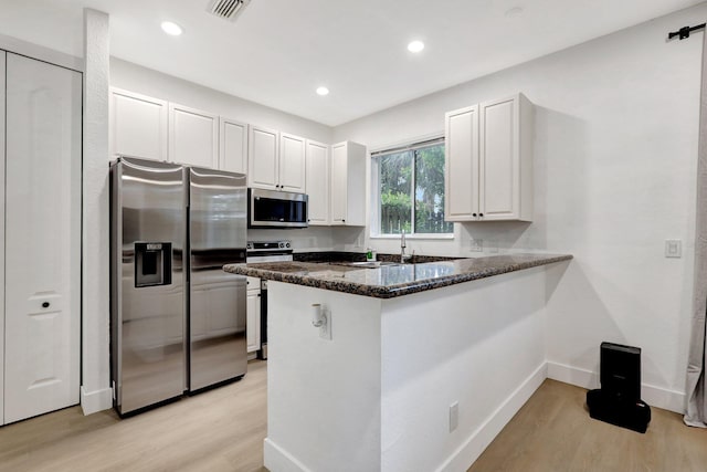 kitchen with stainless steel appliances, white cabinetry, light hardwood / wood-style flooring, and kitchen peninsula