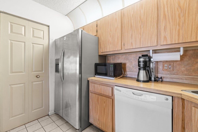 kitchen featuring tasteful backsplash, stainless steel fridge, dishwasher, and light tile patterned floors