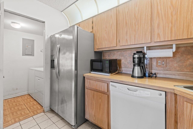 kitchen with white dishwasher, decorative backsplash, electric panel, and washing machine and clothes dryer