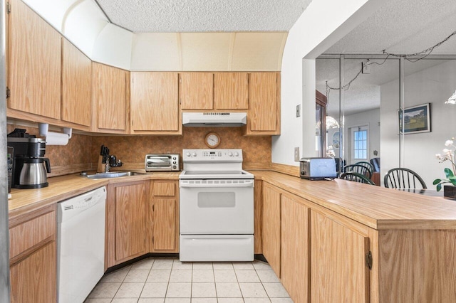 kitchen with sink, light tile patterned floors, kitchen peninsula, white appliances, and decorative backsplash