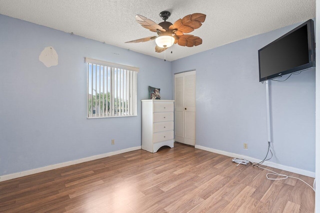 unfurnished bedroom with ceiling fan, a closet, a textured ceiling, and light wood-type flooring