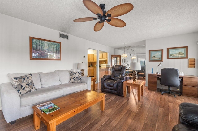 living room featuring ceiling fan, dark wood-type flooring, and a textured ceiling