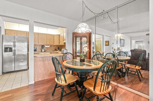 dining space with hardwood / wood-style floors and a textured ceiling