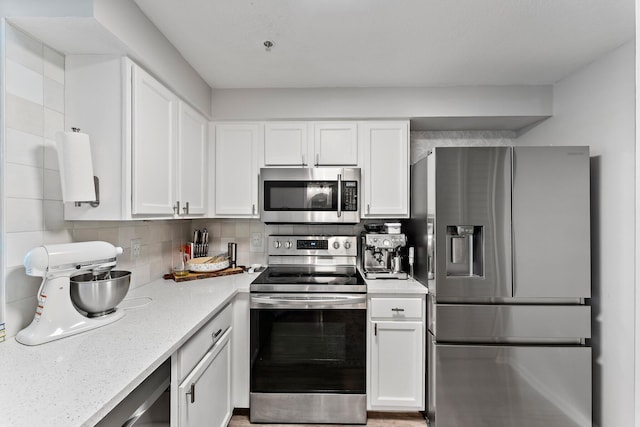 kitchen with tasteful backsplash, light stone counters, stainless steel appliances, and white cabinets