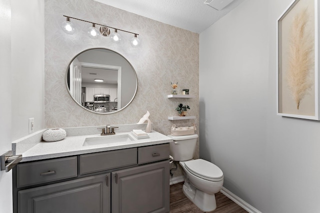 bathroom with wood-type flooring, toilet, vanity, and a textured ceiling