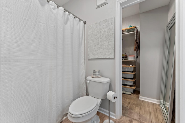 bathroom featuring walk in shower, toilet, and hardwood / wood-style floors