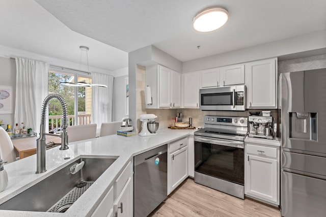 kitchen with pendant lighting, sink, white cabinetry, stainless steel appliances, and decorative backsplash