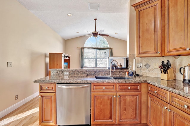 kitchen with stone counters, lofted ceiling, sink, decorative backsplash, and stainless steel dishwasher