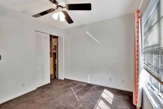 spare room featuring ceiling fan, a textured ceiling, and dark colored carpet