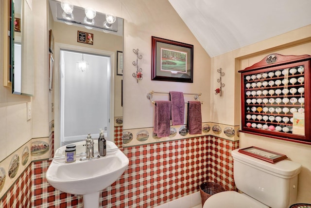 bathroom with sink, toilet, vaulted ceiling, and tile walls