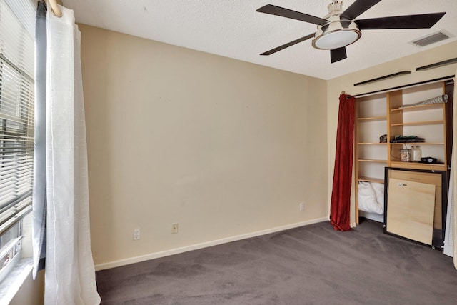 unfurnished bedroom featuring dark carpet, a textured ceiling, ceiling fan, and a closet