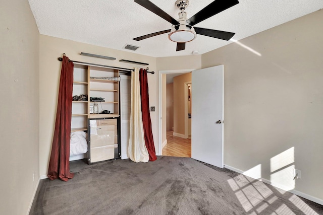 unfurnished bedroom featuring carpet flooring, a textured ceiling, ceiling fan, and a closet