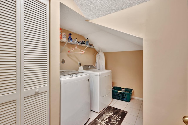 washroom featuring washing machine and dryer, a textured ceiling, and light tile patterned flooring