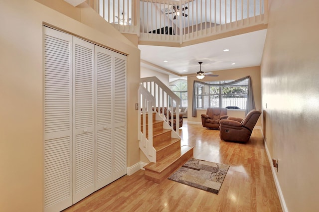 foyer featuring wood-type flooring, a towering ceiling, and ceiling fan