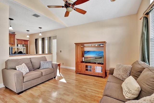 living room featuring ceiling fan, lofted ceiling, a textured ceiling, and light wood-type flooring