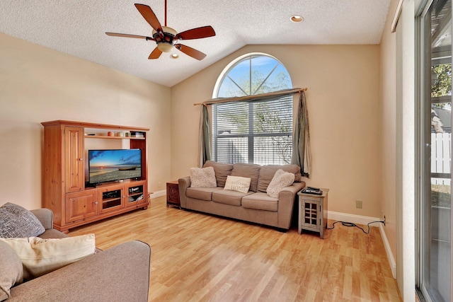 living room featuring lofted ceiling, ceiling fan, a textured ceiling, and light wood-type flooring