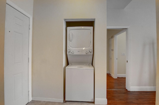 clothes washing area with hardwood / wood-style flooring and stacked washing maching and dryer