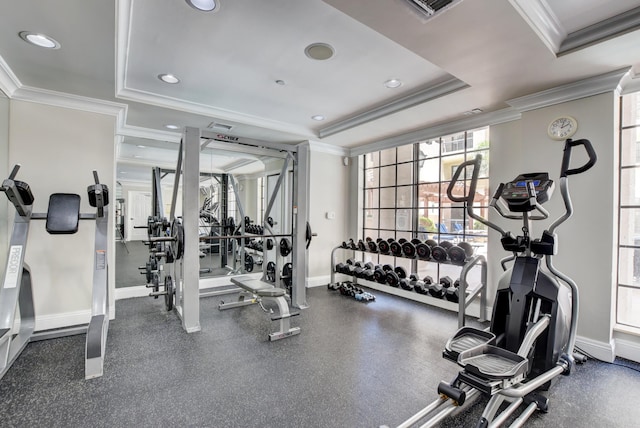 workout area featuring a raised ceiling and ornamental molding