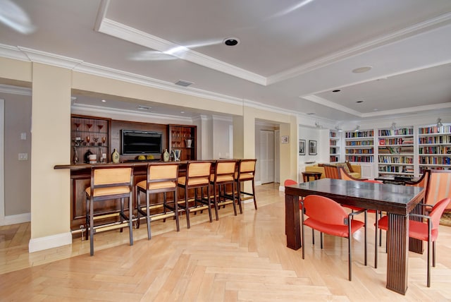 dining room featuring crown molding, built in shelves, light parquet flooring, and bar area