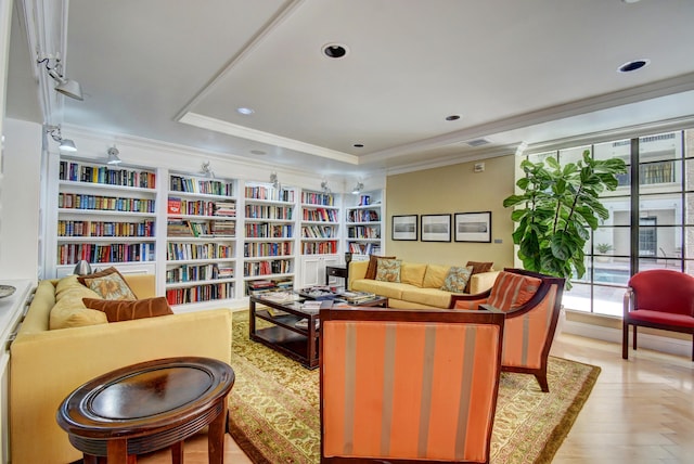 interior space with crown molding, a wealth of natural light, a raised ceiling, and built in shelves