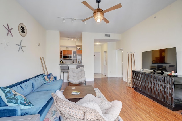 living room with rail lighting, ceiling fan, and light hardwood / wood-style flooring