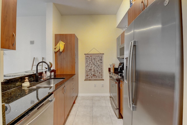 kitchen with light tile patterned floors, stainless steel appliances, sink, and dark stone countertops