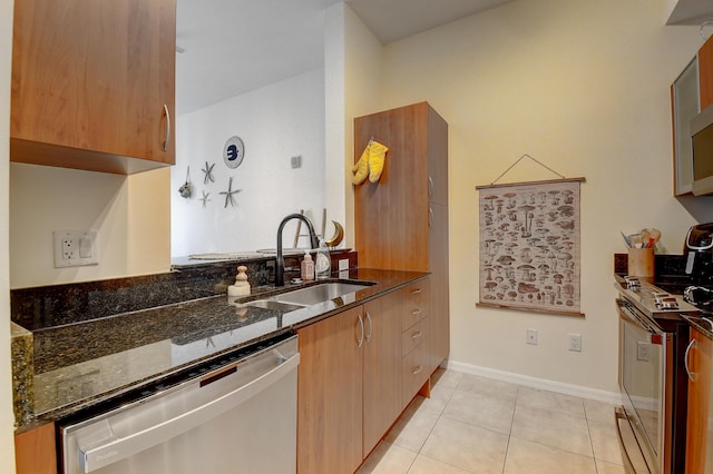 kitchen with sink, light tile patterned floors, dark stone counters, and appliances with stainless steel finishes