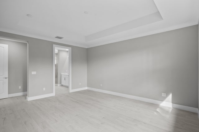 spare room featuring crown molding, a raised ceiling, and light hardwood / wood-style flooring