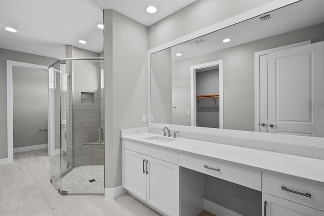 bathroom featuring a shower with door and vanity