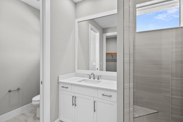 bathroom with tiled shower, vanity, and toilet