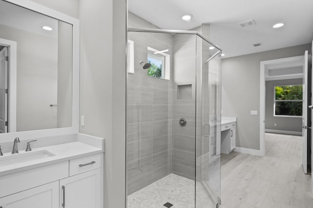 bathroom with hardwood / wood-style flooring, vanity, and an enclosed shower