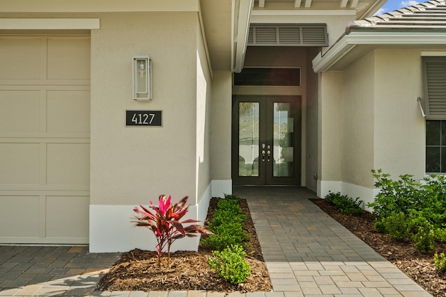 view of exterior entry featuring a garage and french doors