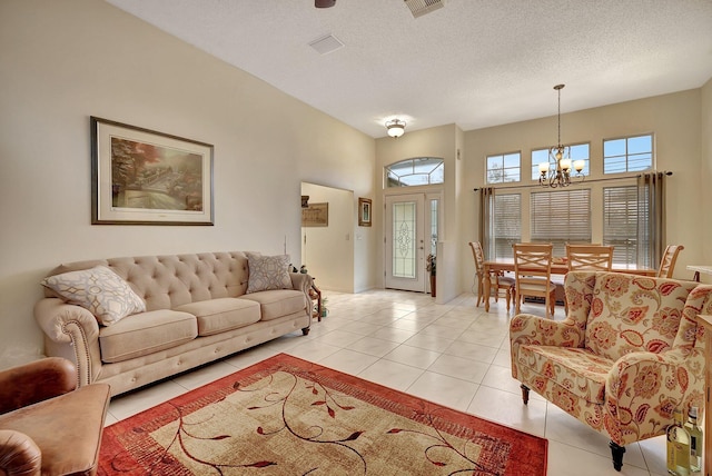 living room featuring an inviting chandelier, light tile patterned floors, a textured ceiling, and a high ceiling