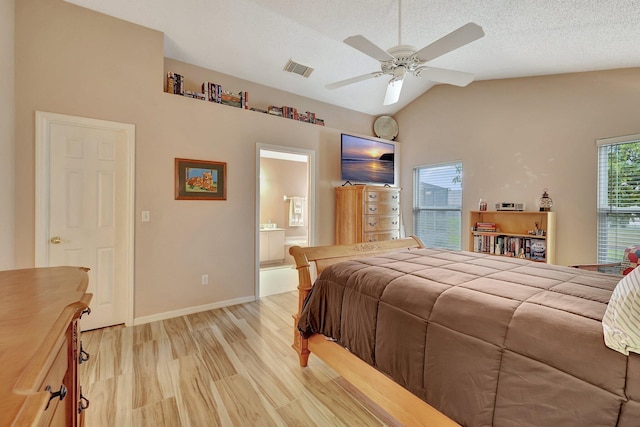 bedroom with vaulted ceiling, ensuite bathroom, ceiling fan, light hardwood / wood-style floors, and a textured ceiling