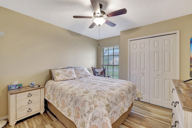 bedroom with a textured ceiling, light hardwood / wood-style floors, a closet, and ceiling fan