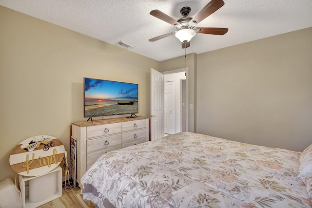 bedroom featuring ceiling fan, light hardwood / wood-style floors, and a textured ceiling