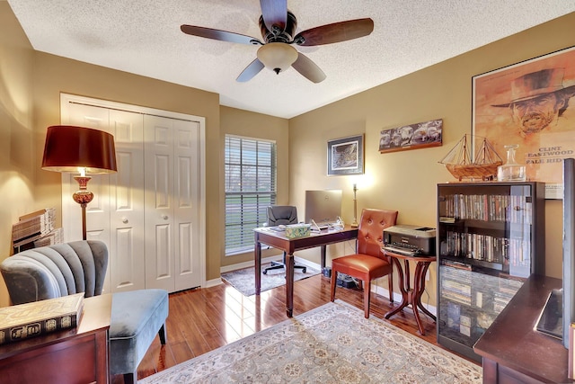 home office featuring ceiling fan, light hardwood / wood-style flooring, and a textured ceiling