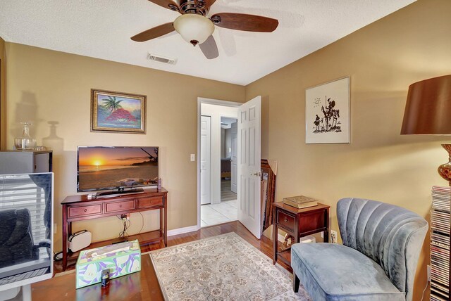 sitting room with a textured ceiling, light hardwood / wood-style flooring, and ceiling fan