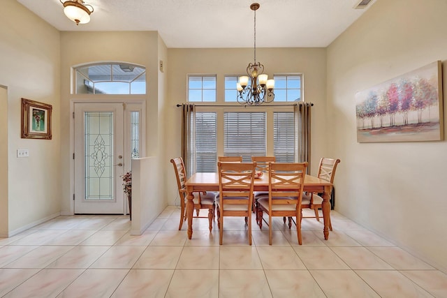 dining area with a towering ceiling, light tile patterned floors, a notable chandelier, and a textured ceiling