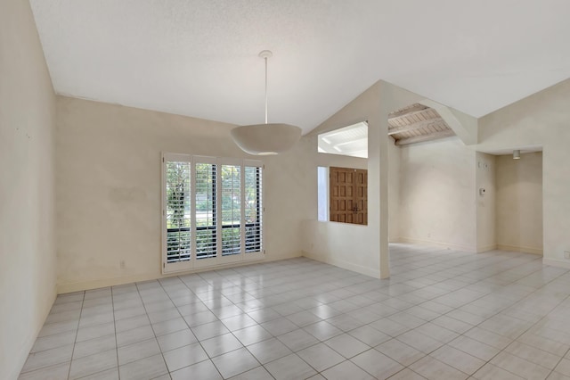 tiled empty room featuring vaulted ceiling