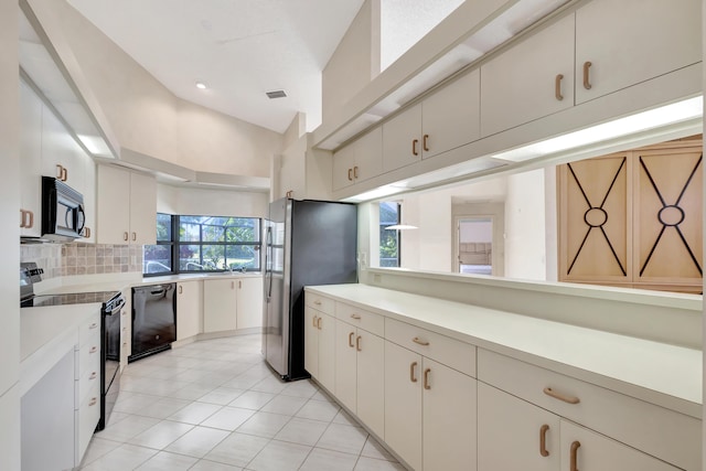 kitchen with tasteful backsplash, light tile patterned floors, vaulted ceiling, and black appliances