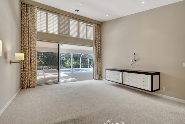 spare room featuring light carpet and a high ceiling