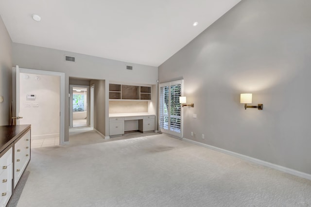 unfurnished bedroom with built in desk, high vaulted ceiling, and light carpet