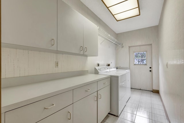 washroom featuring washer and dryer, cabinets, and light tile patterned flooring