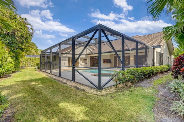 rear view of house with glass enclosure and a lawn